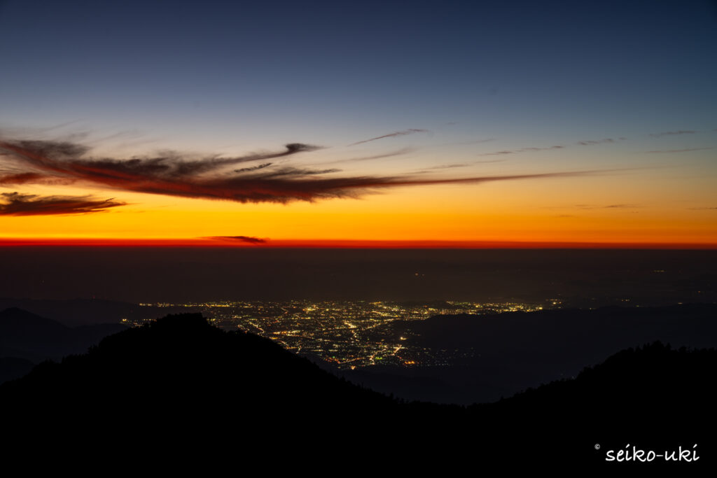 夕焼けの残る空の下、雲の切れ間に見える街明かり
